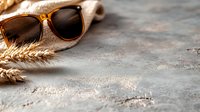 Stylish brown sunglasses with wheat stalks on textured concrete background, perfect for summer fashion accessories and lifestyle content.