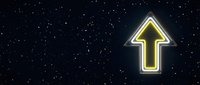 Glowing yellow neon arrow pointing upward against starry night sky background for business growth and success concepts.