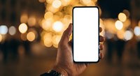 Hand holding smartphone with blank white screen against warm bokeh lights background for mobile app mockup and digital technology presentation.