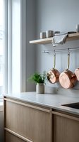Modern Scandinavian kitchen interior with copper pots hanging on rail, wooden cabinets, marble countertop and minimalist design for home decor inspiration.