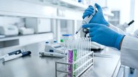 Scientist in blue gloves conducting laboratory research with test tubes and pipette in modern medical facility for scientific analysis and experimentation.
