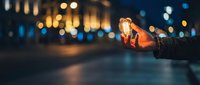Hand holding glowing light bulb against blurred city night background with bokeh lights. Concept of innovation, creativity and bright ideas.