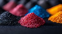 Colorful plastic polymer granules in piles on dark background. Raw material for injection molding and manufacturing. Industrial plastic pellets for production.