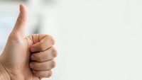 Hand showing thumbs up gesture against white background expressing approval and positive feedback for business presentations.
