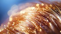 Glowing fiber optic strands with golden bokeh lights creating abstract technology background pattern. Modern communication concept.