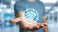 Person in casual blue shirt holding glowing wifi symbol in palm, representing wireless connectivity, internet access, and digital communication technology in modern business environment.