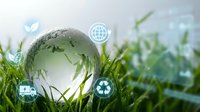 Green glass globe with world map sitting in fresh grass with environmental sustainability icons representing eco-friendly technology and conservation.