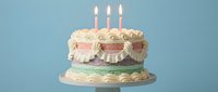 Birthday cake with lit candles and cream frosting on blue background for celebration party dessert concept.