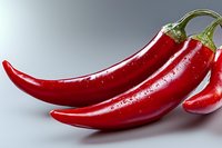 Fresh red chili peppers with water drops on gray background, macro shot showing texture and glossy surface for food and cooking concepts.