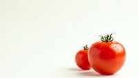 Fresh red tomatoes with green stems on clean white background for healthy cooking and organic food concepts.