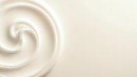 Creamy white swirl texture with smooth flowing curves creating elegant spiral pattern on neutral beige background for cosmetic and skincare applications.