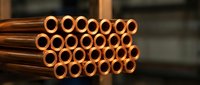 Stack of shiny copper pipes with circular openings arranged in rows, industrial plumbing materials for construction and manufacturing projects.