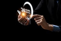 Businessman hands holding glowing 24 hours service icon with light effect on dark background for customer support and assistance concepts.