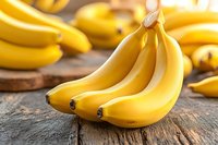 Fresh ripe yellow bananas on rustic wooden background with soft natural lighting, close up view of tropical fruits for healthy eating and nutrition.