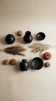 Autumn flat lay with black ceramic pottery, orange pumpkins and dried pampas grass on neutral beige background for seasonal home decor and styling projects.
