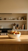 Wooden bowl filled with fresh apples on kitchen counter with built-in shelving and appliances in background, suitable for home decor and lifestyle content.