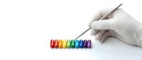 Gloved hand arranging colorful rainbow capsule pills in a row with tweezers on white background, medicine and pharmacy concept.