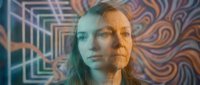 Young woman with long hair in futuristic digital environment with colorful geometric patterns and neon lighting effects for technology concepts.