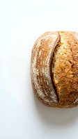 Freshly baked artisan sourdough bread loaf with golden crust and deep scoring cut, isolated on white background for bakery and food design projects.