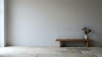 Minimalist wooden bench against white wall with dried flowers in ceramic vase on natural stone floor creating serene modern interior design space.