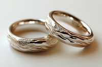 Elegant gold wedding rings with flowing wave patterns and sparkling diamond accents on neutral background for romantic jewelry designs.