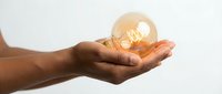 Hands holding glowing light bulb symbolizing innovation, creativity and bright ideas for business solutions and inspiration concepts.