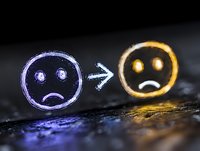 Glowing neon sad faces with arrow showing emotional transformation on dark background, depicting mental health and mood change concept for psychology designs.