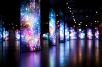 Digital art installation with glowing cosmic displays on vertical panels creating colorful reflections on dark floor in modern gallery space. Immersive multimedia experience.