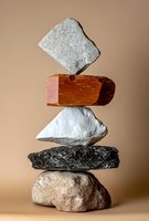 Stacked stones and brick balanced in tower formation against neutral background, isolated for design use on various materials.