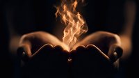 Hands cupped together holding magical flame fire energy glowing warmly against dark background symbolizing power protection hope and spiritual connection.