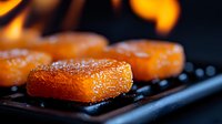 Grilled salmon pieces with crispy caramelized crust on dark background, extreme close up macro shot showing texture and juicy meat surface.