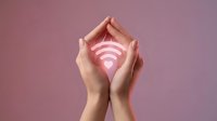 Hands cupping glowing pink wifi symbol against soft background, representing internet security, connectivity protection, and wireless network safety for technology concepts.