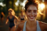 Young athletic woman smiling after outdoor workout with friends in golden hour sunlight. Fitness lifestyle and healthy living concept for wellness campaigns.