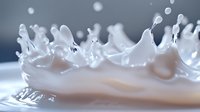 Milk crown splash with droplets frozen in time against dark background, capturing liquid dynamics in high-speed macro photography showing fluid motion and surface tension.