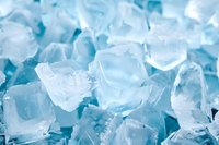 Fresh ice cubes with blue tint background, macro close-up showing crystalline structure and transparency. Cold refreshing texture for beverage and cooling concepts.