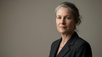 Middle-aged woman with gray hair wearing black blazer against neutral background, suitable for corporate, business, and professional portraits.