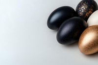 Luxurious Easter eggs in black, gold, and glitter finishes arranged on white background. Minimalist holiday composition with copy space for seasonal designs.