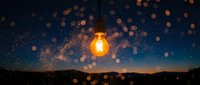 Glowing light bulb floating above landscape with bokeh particles and starry night sky, symbolizing innovation, creativity, and bright ideas for business concepts.