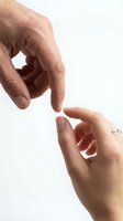 Two hands reaching toward each other in gentle touching gesture on white background symbolizing human connection, support and care in relationships.