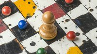 Wooden chess pawn on distressed checkerboard with colorful game pieces scattered around. Vintage board game concept with grunge texture and worn surface.