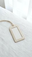 Beige leather luggage tag with clear window on white linen fabric background for travel accessories and identification purposes.