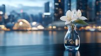 Glass vase with white lily flowers on table against blurred city skyline at dusk. Urban floral arrangement for interior design and home decor concepts.