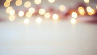 Soft blurred bokeh lights creating warm golden glow over light textured surface for holiday backgrounds, wedding invitations, greeting cards and festive designs.