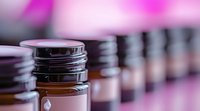 Glass cosmetic jars with brown cream or serum arranged in row against pink blurred background, selective focus on front container, luxury skincare concept.