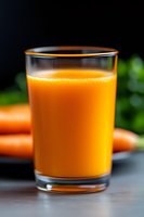 Fresh carrot juice in clear glass with blurred carrots in background, vibrant orange color and natural texture captured in macro photography on dark surface.