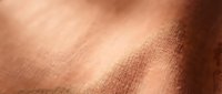 Close-up of warm copper-toned fabric with soft natural lighting, showcasing textile weave and material texture for design and fashion projects.