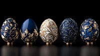 Luxurious decorated Easter eggs in deep blue and gold colors with ornate floral patterns arranged in row on dark reflective surface. Elegant holiday composition.
