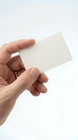 Male hand holding blank white business card mockup on light background for branding and corporate identity design projects.
