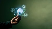 Hand holding glowing light bulb with green energy icons, symbolizing sustainable innovation, eco-friendly solutions, and renewable power concepts.