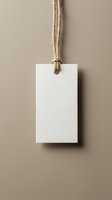 Blank white paper tag with natural rope string hanging on beige background for branding and product labeling mockup design projects.